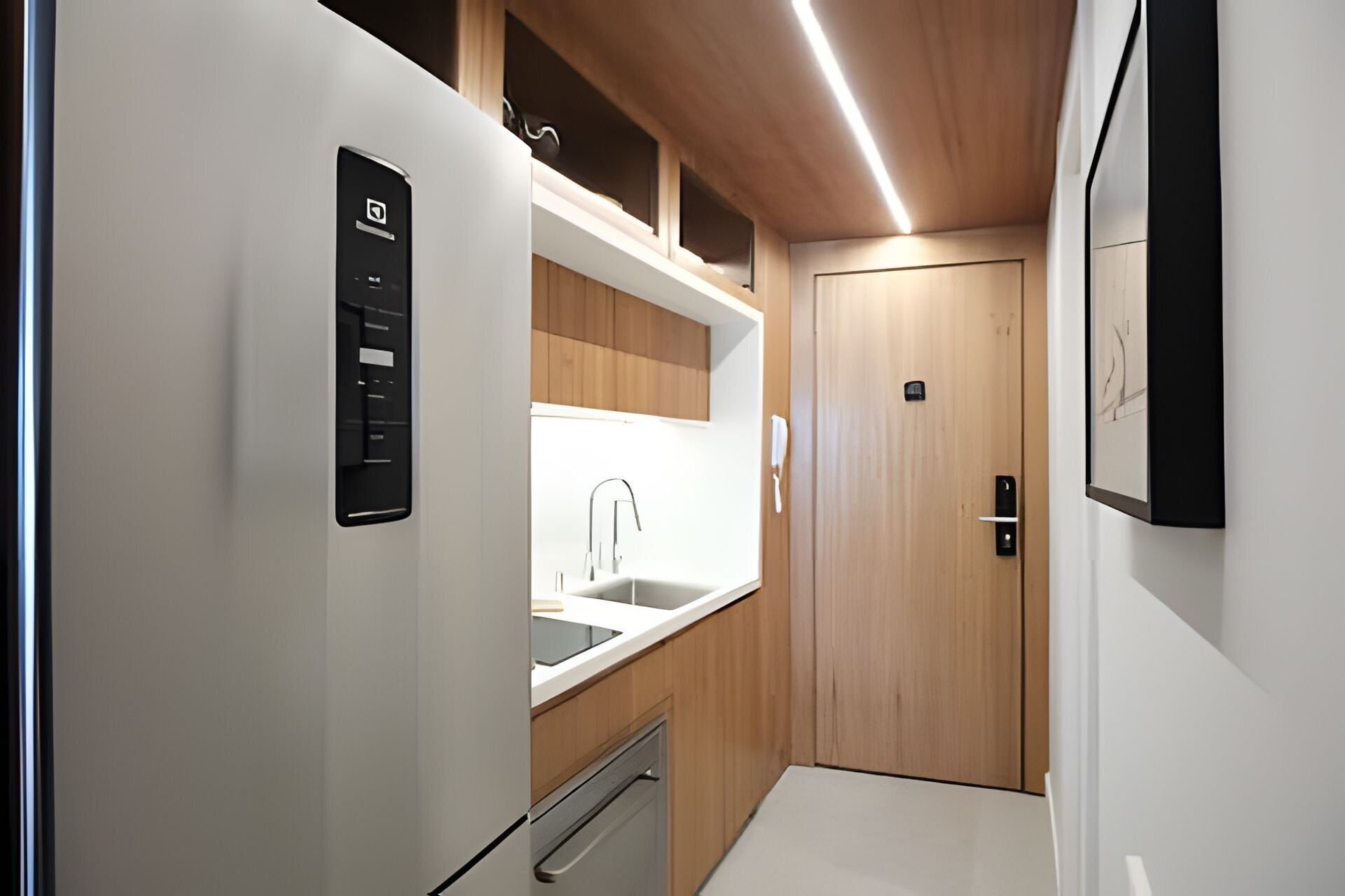 Een functionele keuken met een inbouwkoelkast, een spoelbak en houten keukenkastjes.