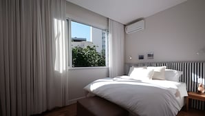 Une chambre moderne avec un grand lit, une fenêtre avec des rideaux, une table de chevet et un radiateur.