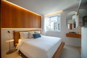 A modern bedroom with a large bed, bedside table, and a mirror. - Leblon – Renovated & Steps from the Beach (Rio de Janeiro)