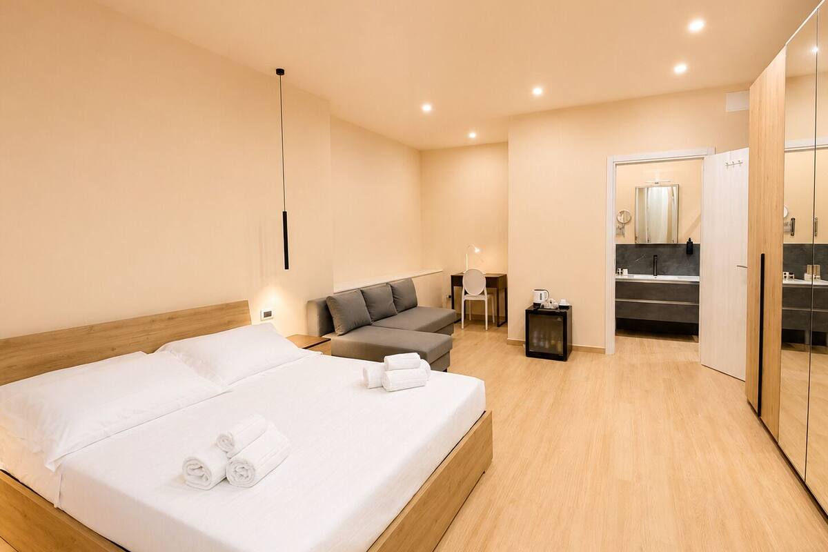 Une chambre d’hôtel moderne, dotée d’un grand lit, d’un canapé, d’un bureau et d’une salle de bain avec un miroir et un lavabo.