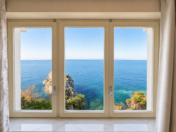 A room with a large window overlooking a coastal view.