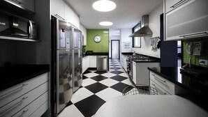 Une cuisine moderne dotée d’appareils électroménagers en acier inoxydable, d’un carrelage à motifs et d’un pare-feu vert.