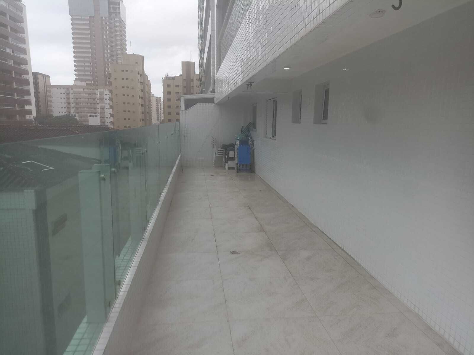 Un corridoio stretto con una ringhiera in vetro da un lato e un muro bianco dall'altro, che conduce a una porta in fondo.