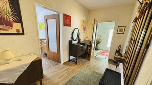 Une pièce comprenant un lit, une commode, un miroir, une chaise et une porte donnant sur une autre pièce.