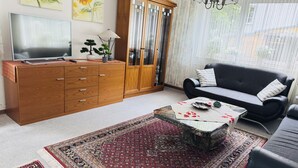 Un salon comprenant un meuble en bois, une télévision, un canapé, une table basse et un grand tapis.