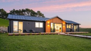 Una casa moderna con una amplia terraza, un área de estar al aire libre cubierta y un césped.