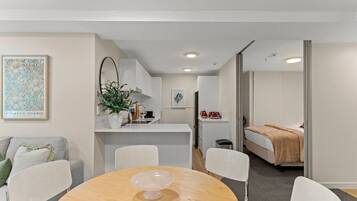 A modern, compact hotel room with a dining area, kitchenette, and a bed.