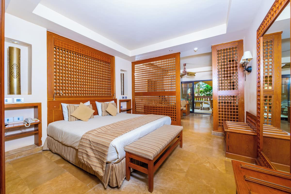 A spacious bedroom with a large bed, wooden headboard, and a bench.