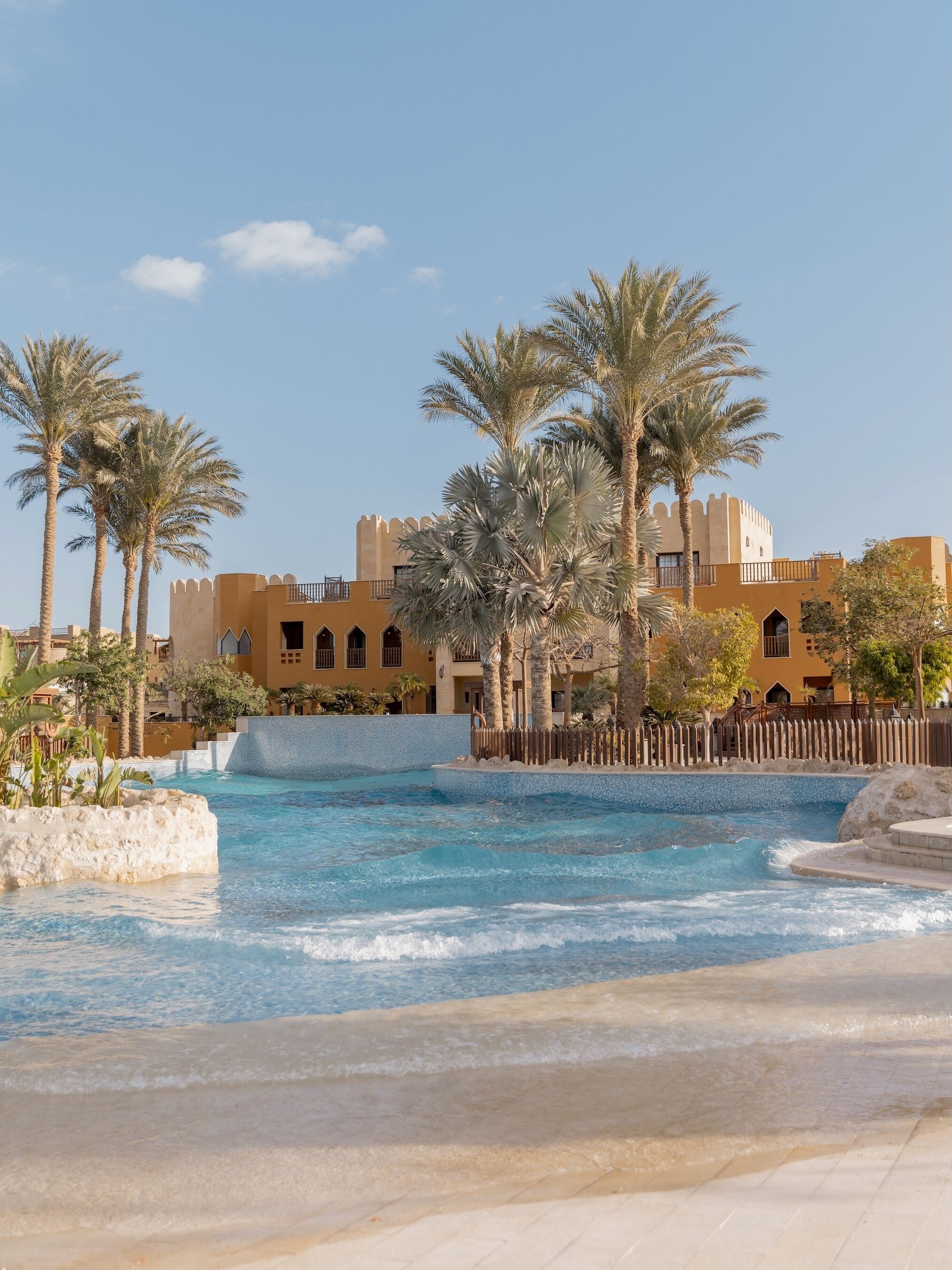 Un resort con piscina, palme e architettura tradizionale.
