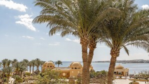 A coastal resort with palm trees, a beach, and Mediterranean-style architecture. - Grand Waterworld Makadi couples and families only (Makadi Bay)