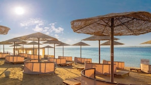 A beach with sun umbrellas and lounge chairs arranged for guests. - Grand Waterworld Makadi couples and families only (Makadi Bay)