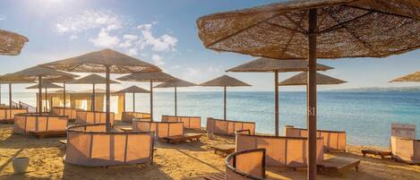 A beach with sun umbrellas and lounge chairs arranged for guests.