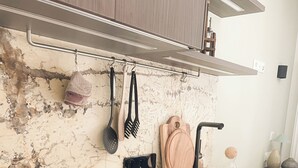 A kitchen with a marble countertop, black stove, and hanging utensils. - Apartment Weißhorn (Barbian)