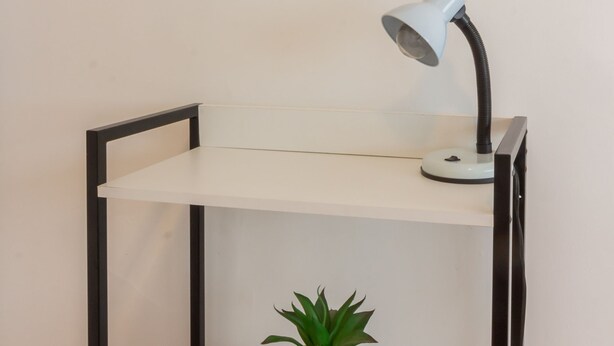 A desk with a desk lamp, a potted plant, and a framed picture on the wall. - Ae302 Zona1 in Rio de Janeiro (Rio de Janeiro)