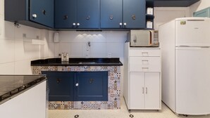 A kitchen with blue cabinets, a white refrigerator, and a microwave. - Ae302 Zona1 in Rio de Janeiro (Rio de Janeiro)