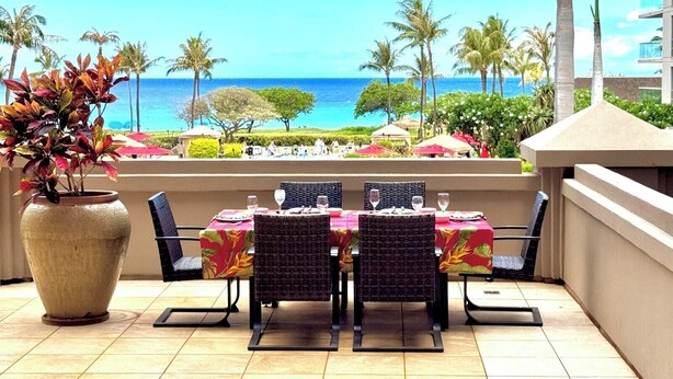 An outdoor dining area with a view of the ocean, a large potted plant, and a tiled floor. - Honua Kai | Ocean View 5 BR, Sleeps 16 | Car Incl. w/ 6+ Nights | HKH ML-1616 by KBM (Lahaina)