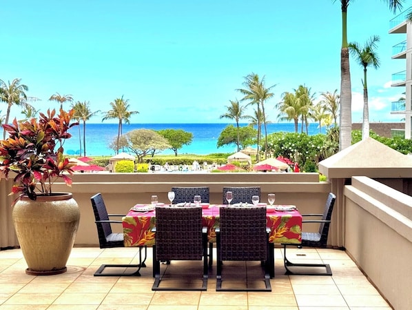 An outdoor dining area with a view of the ocean, a large potted plant, and a tiled floor.