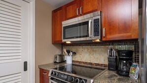 A kitchen with wooden cabinets, a stainless steel microwave, a gas stove, and a coffee maker. - Honua Kai | Ocean View 5 BR, Sleeps 16 | Car Incl. w/ 6+ Nights | HKH ML-1616 by KBM (Lahaina)