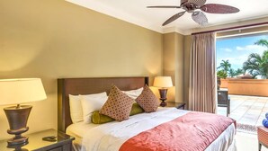 A hotel room with a bed, two bedside lamps, a ceiling fan, and a view of the outdoors.