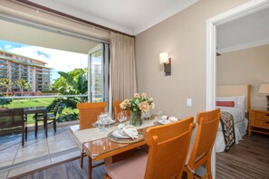 Ein Hotelzimmer mit Balkon, einem Esstisch gedeckt mit Tellern und Gläsern sowie einem Bett mit Nachttisch.