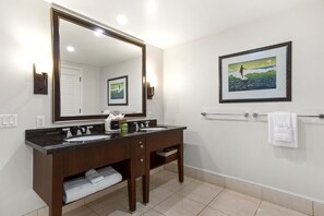 Un baño con dos lavamanos, un espejo grande, un cuadro en la pared y un perchero para toallas.