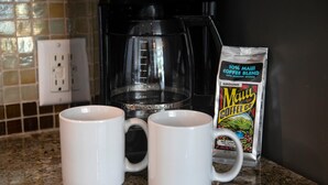 Two white mugs on a granite countertop, a black coffee maker, and a packet of Maui Coffee Blend. - Honua Kai | Ocean View 5 BR, Sleeps 14 | Car Incl. w/ 6+ Nights | HKH ML-1634 by KBM (Lahaina)