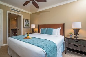 A hotel room with a bed, a nightstand, a lamp, a bottle of champagne, and a ceiling fan.