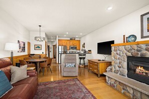 Una sala de estar con chimenea, un comedor y una cocina al fondo.