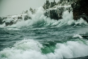 A coastal scene with waves crashing against a rocky shore.