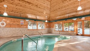 A pool area with wooden walls, a lifeguard sign, and a view of the outside.