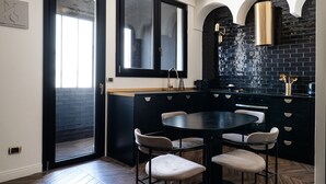 A modern kitchen with a black and white color scheme, featuring a round dining table with chairs, a black countertop, and a window above the sink. - XOXO from Bari by Wonderful Italy (Bari)