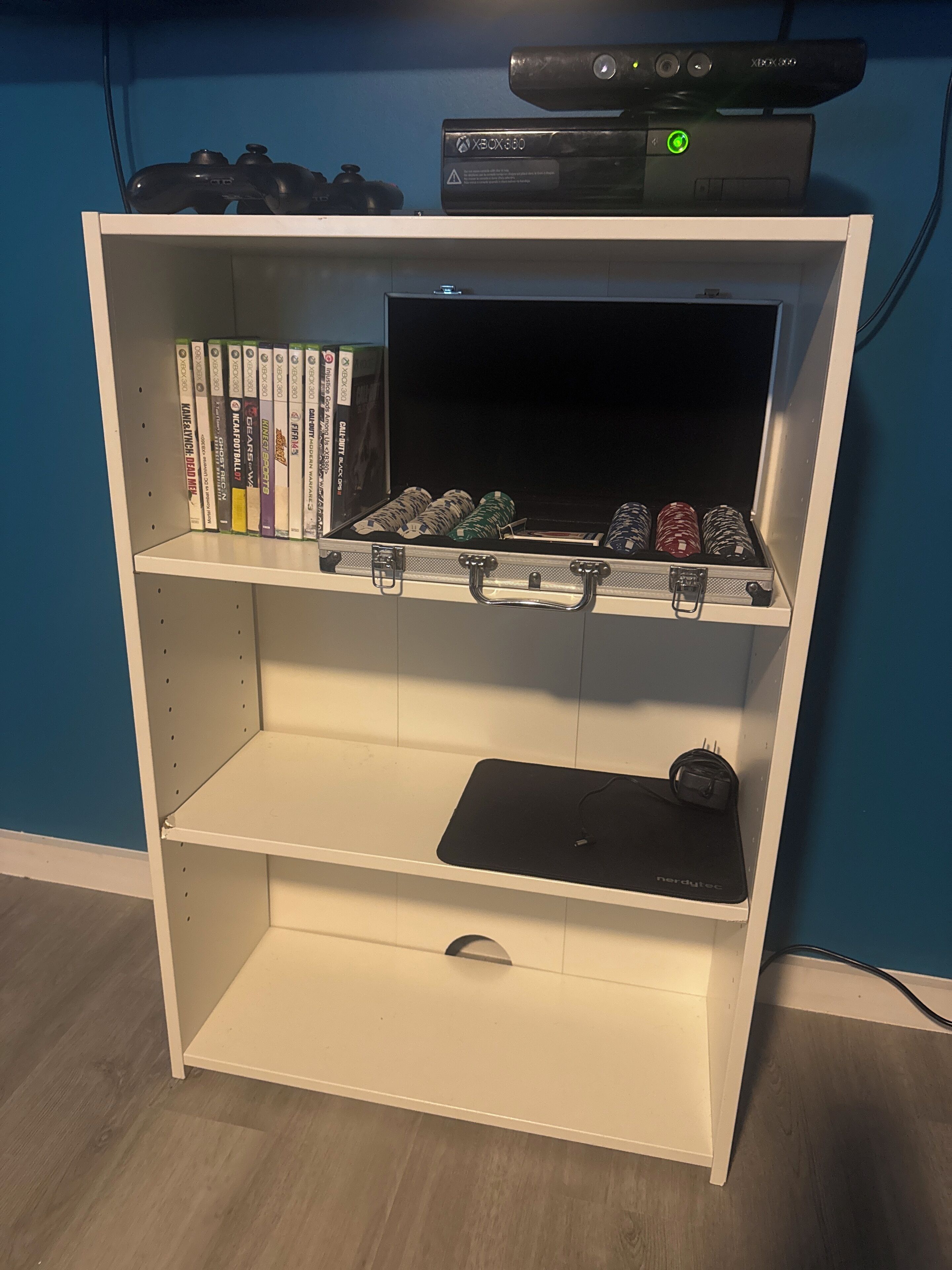 Un mueble blanco de entretenimiento con un televisor de pantalla plana, una consola de videojuegos y una colección de juegos.