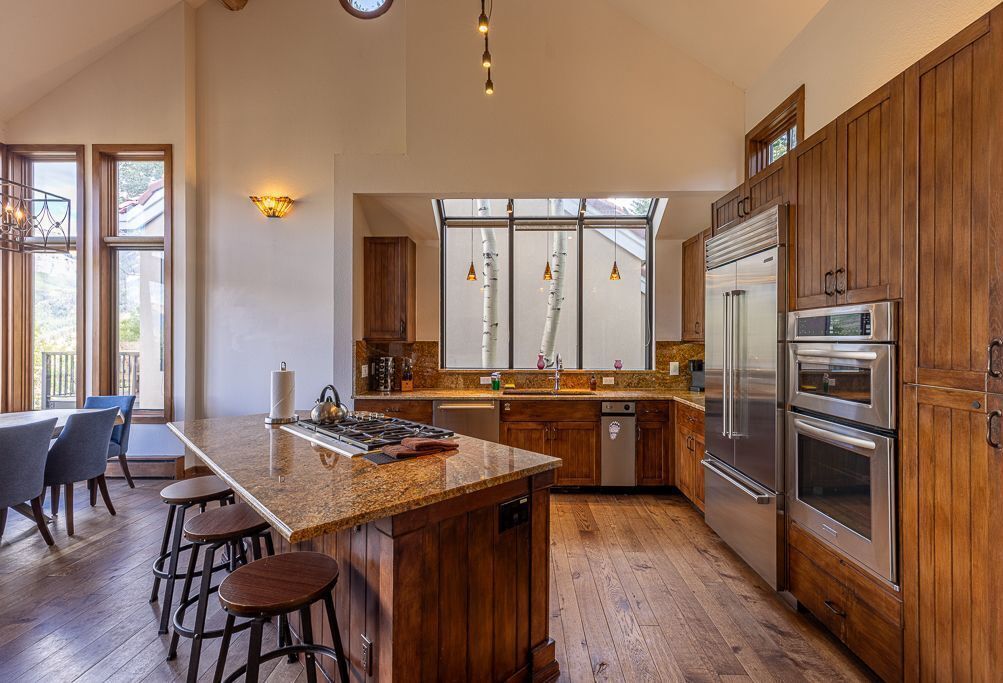 Une cuisine spacieuse dotée de meubles en bois, d’appareils électroménagers en acier inoxydable et d’un grand îlot central avec des tabourets.