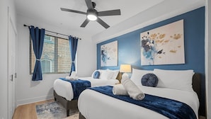 A hotel room with two beds, a ceiling fan, artwork on the walls, and a window with curtains. - PFR Suites - Highland, 3BR 2BA Shadyside Condo, 2 Decks and Off-Street Parking (Pittsburgh)