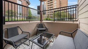 A balcony with wicker furniture, a glass table, and a view of buildings and greenery. - Pristine Double King 3BR suite | A+ Location| ADA| (Pittsburgh)
