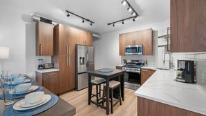 A modern kitchen with wooden cabinets, stainless steel appliances, and a central island with stools. - Immaculate Double King Suite | 4 beds | 2 Decks (Pittsburgh)