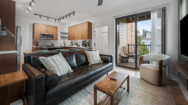 A modern living room with a leather sofa, a wooden coffee table, and a TV stand. - Immaculate Double King Suite| 2 Decks| A+ Location (Pittsburgh)