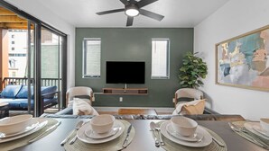 A dining area with a table set for four, a ceiling fan, and a flat-screen TV mounted on the wall. - Immaculate Double King Suite| 2 Decks| A+ Location (Pittsburgh)