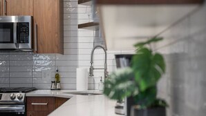 A modern kitchen with stainless steel appliances, a white tiled backsplash, and a wooden cabinet. - Immaculate Double King Suite| 2 Decks| A+ Location (Pittsburgh)