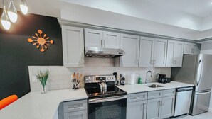 A modern kitchen with stainless steel appliances, white cabinetry, and a black accent wall. - Royaleux / 4 King Beds / Sleep 16 / Pool Table (Philadelphia)