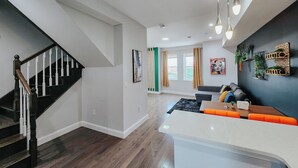 A modern living room with a staircase, a dining area, and a kitchen. - Royaleux / 4 King Beds / Sleep 16 / Pool Table (Philadelphia)