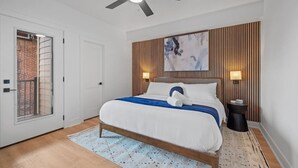 A modern bedroom with a bed, ceiling fan, and artwork on the wall.