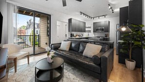 A modern living room with a black leather sofa, a round coffee table, and a view of the city through large windows.