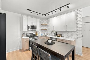 A modern kitchen with white cabinets, a stainless steel stove, and a black countertop.
