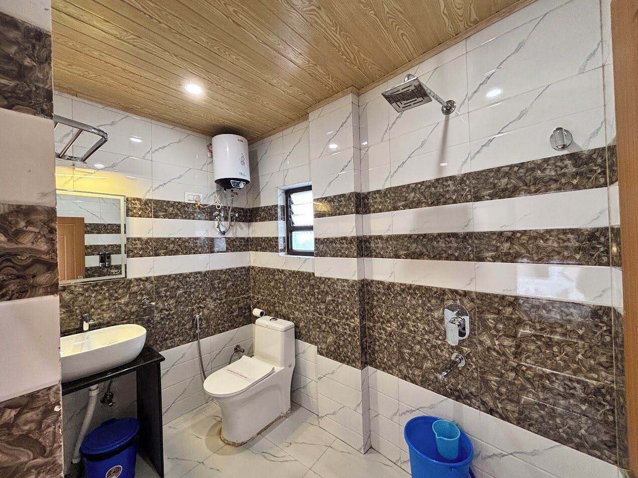 A bathroom with a marble and wood design, a sink, toilet, and shower.