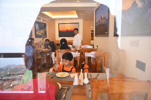 A restaurant with wooden furniture and a large painting of a sunset on the wall.