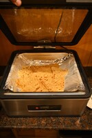 Una freidora de aire con tortillas envueltas en papel de aluminio.