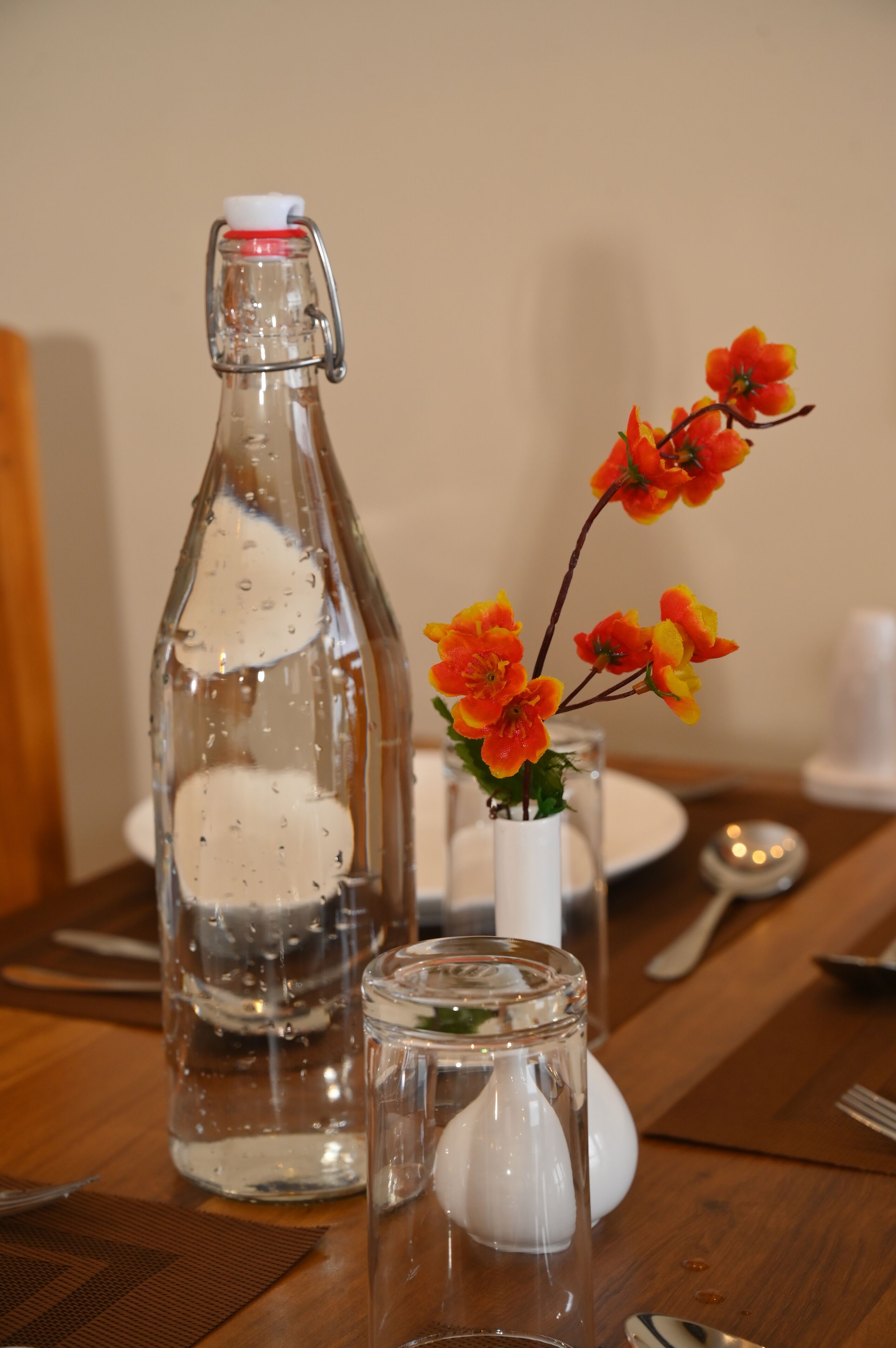 Une table avec une bouteille, un petit vase de fleurs et un salier.