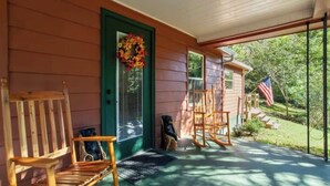Eine Veranda mit Holzstühlen, einer grünen Tür und einer US-amerikanischen Flagge.