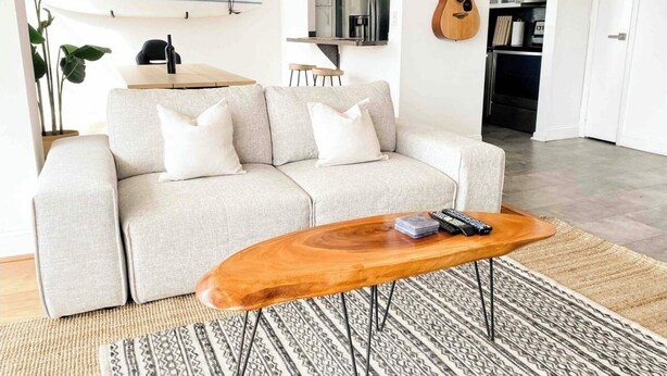 Ein Wohnzimmer mit einer Couch, einem Couchtisch und einer Gitarre im Hintergrund.